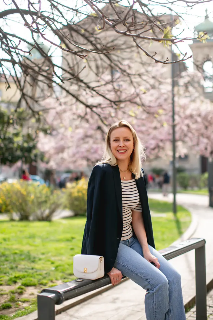 Svitlana sitting on a railing in a park, smiling at the camera.